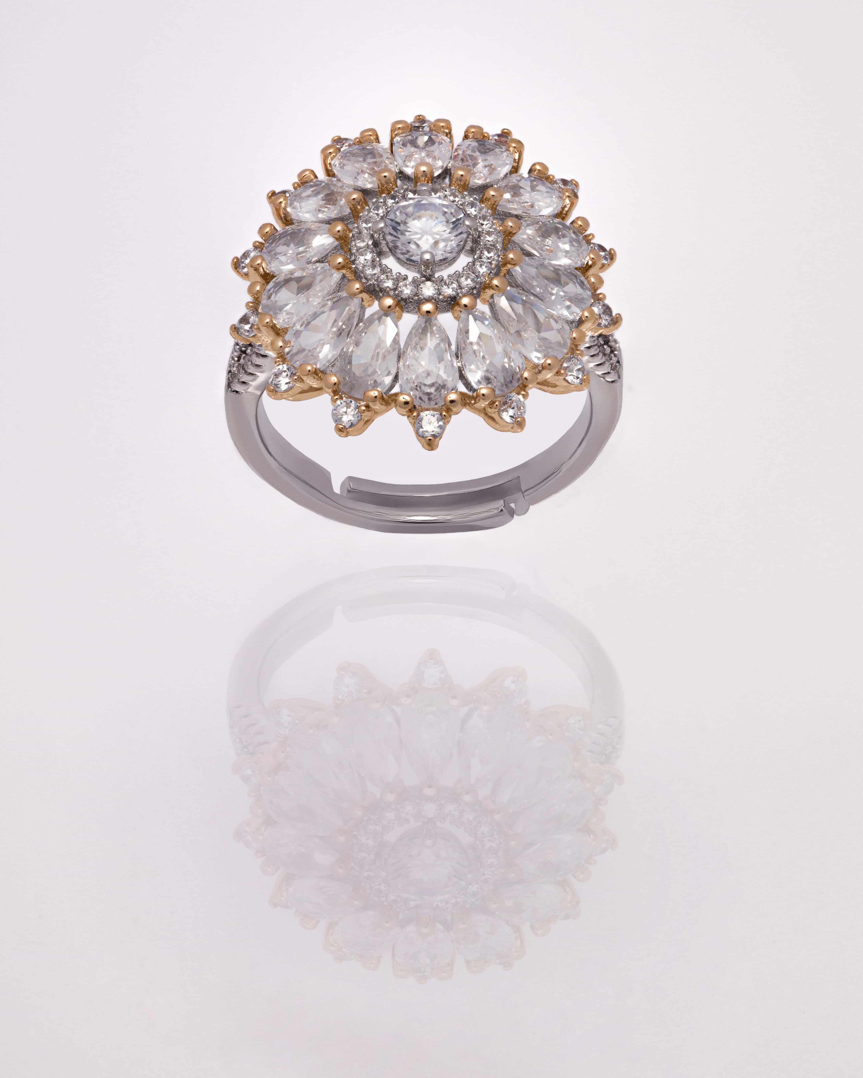 A close up of a white golden ring with a large oval diamond stone surrounded by small diamonds set on a white background.